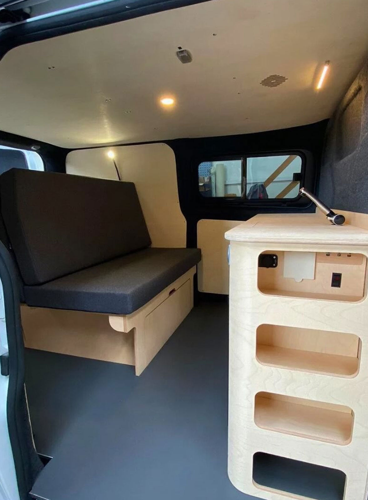 Meuble transversal Exokit installé dans un Ford Transit Custom L1H1 avec réfrigérateur, évier, douchette extérieure et prises électriques intégrés