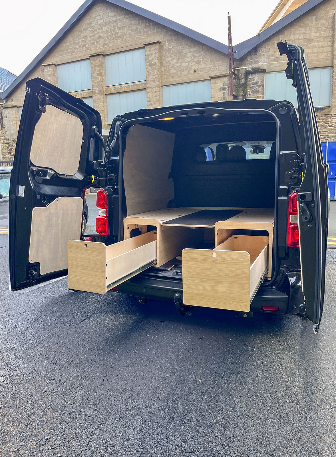 Tiroirs extérieurs gauche et droite du kit banquette en U Exokit pour Opel Vivaro B XL, accessibles depuis l'extérieur sans ouvrir les portes